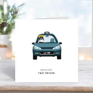 Puede incluir: Tarjeta de felicitación con una ilustración de taxi verde azulado. Un gato con gorro de taxista está en el asiento del conductor. La matrícula dice "L1 ON". El texto "WORLD'S BEST TAXI DRIVER" está debajo del coche.