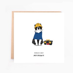 Peut inclure: Une carte de vœux carrée illustrée d'un chat noir et blanc portant un casque de chantier jaune et une chemise bleue, à côté d'une boîte à outils noire et jaune. Le texte en dessous indique WORLD'S BEST MECHANIC en lettres capitales noires.