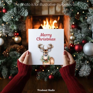 Peut inclure: Une carte blanche avec le texte "Merry Christmas" en lettres rouges. Une illustration aquarelle d'un cerf brun avec des bois portant une couronne verte autour du cou est sur la carte.