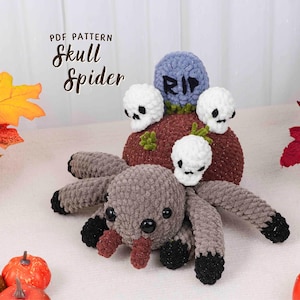 May include: A crocheted Halloween spider with a tombstone and skulls. The spider is gray with black accents and red fangs. The tombstone is blue with "RIP" on it. The text "PDF PATTERN Skull Spider" is at the top.