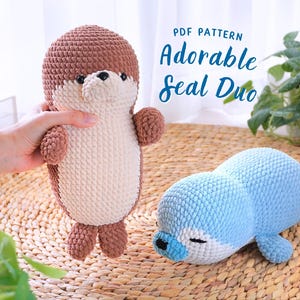 May include: PDF pattern for crocheting a pair of adorable seal plushies. One seal is brown and white, the other is blue and white. Both are lying on a woven mat.