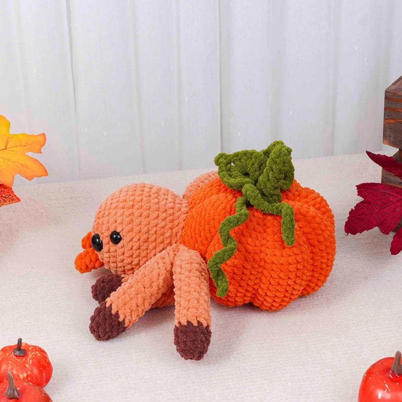 May include: A handmade crochet spider with an orange pumpkin body. The spider has an orange body, legs, and head, with dark brown feet and black eyes. The pumpkin has green vines and leaves. A festive fall decoration.