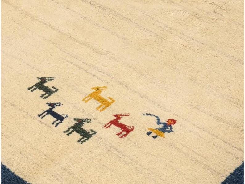 May include: Cream-colored rug with a striped pattern and a dark blue border. The rug features colorful embroidered animal figures in green, yellow, red, and blue. The rug is a decorative floor covering.