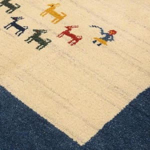 May include: Cream-colored rug with a blue border and a pattern of colorful animal figures. The animals are in shades of green, yellow, and red. The rug has a textured appearance.