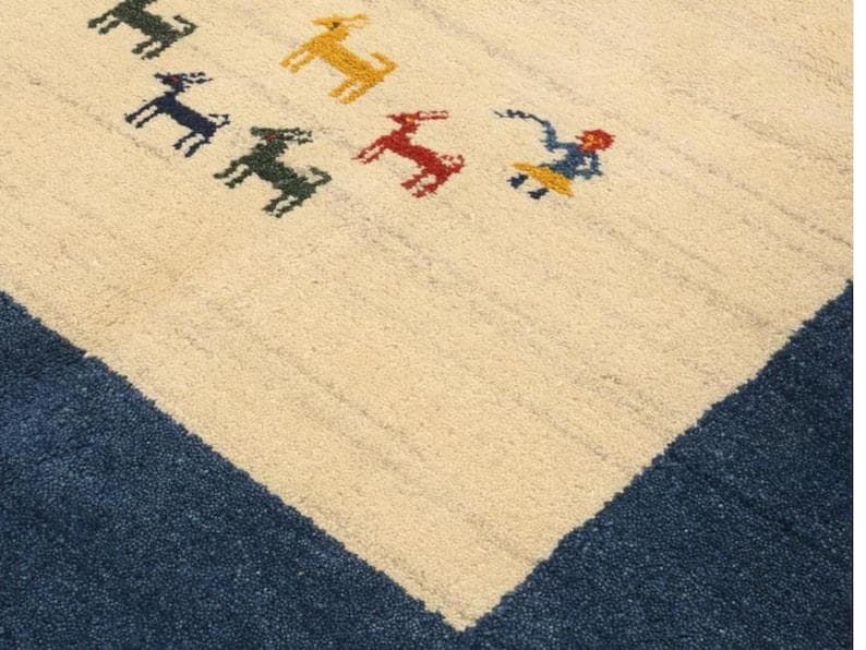 May include: Cream-colored rug with a blue border and a pattern of colorful animal figures. The animals are in shades of green, yellow, and red. The rug has a textured appearance.