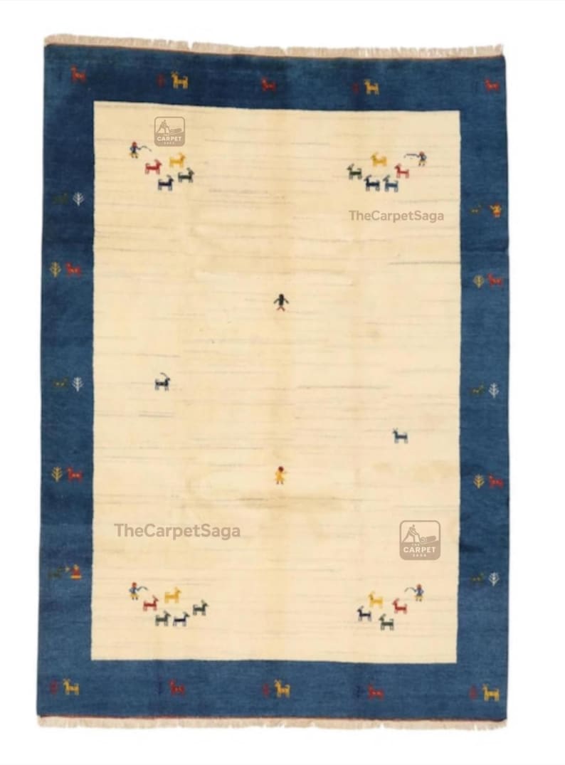 May include: Rectangular rug with a cream-colored center and a dark blue border. The rug features small, colorful figures and the text "TheCarpetSaga". The rug has a traditional design.