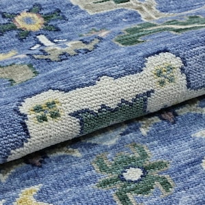 Könnte beinhalten: Nahaufnahme eines blauen Teppichs mit einem geometrischen Muster in Blautönen, Grün, Gelb und Weiß.