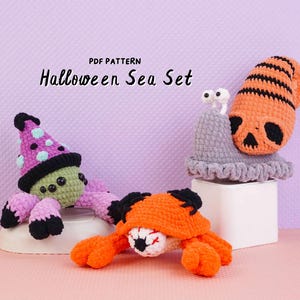 May include: Three crocheted sea creatures including a green spider with a purple hat, an orange crab with a central eyeball, and a gray snail with an orange skull-patterned shell. The text PDF PATTERN Halloween Sea Set is visible.