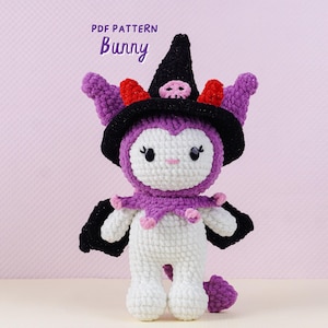 May include: A handmade crochet bunny doll wearing a black witch hat with a skull, purple ears, and a purple and pink collar. The doll is white with purple accents and black wings. The text "PDF PATTERN Bunny" is at the top.