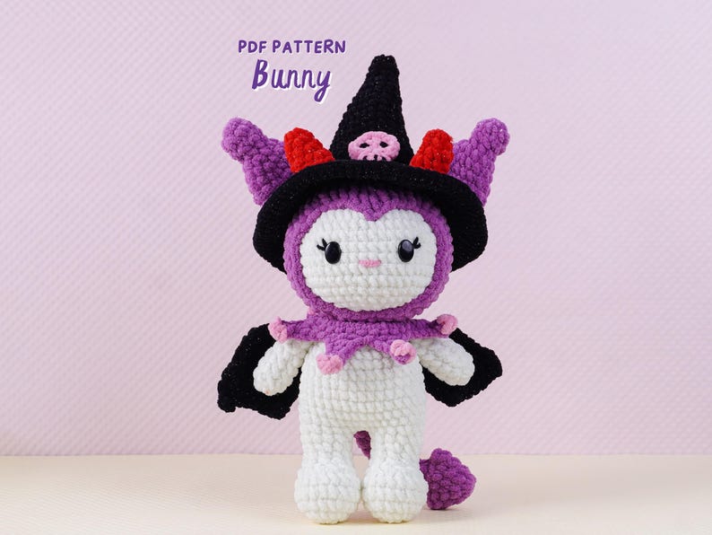 May include: A handmade crochet bunny doll wearing a black witch hat with a skull, purple ears, and a purple and pink collar. The doll is white with purple accents and black wings. The text "PDF PATTERN Bunny" is at the top.