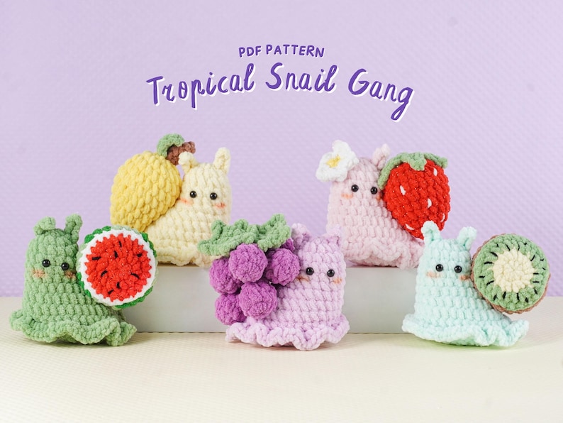 May include: A collection of crocheted snail figures, each adorned with a different tropical fruit. The snails are in various colors, including green, yellow, pink, and blue. The text "Tropical Snail Gang" is displayed above the figures.