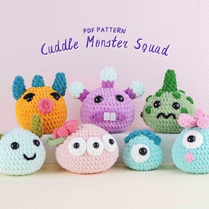 Puede incluir: Colección de siete peluches de monstruos de ganchillo coloridos. Cada monstruo tiene características únicas, incluyendo cuernos, lazos y diferentes expresiones faciales. El texto "PDF Pattern Cuddle Monster Squad" se muestra arriba.