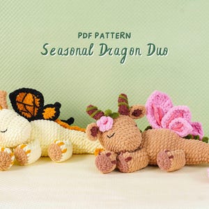 May include: Two crocheted dragon plushies in cream and brown, with orange, black, and pink accents. The cream dragon has butterfly wings, while the brown dragon has flower details. The text "PDF PATTERN Seasonal Dragon Duo" is at the top.