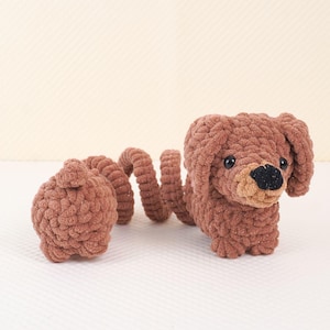 Puede incluir: Un juguete de dachshund de crochet marr&oacute;n con una cola larga y rizada. El juguete est&aacute; hecho de hilo suave y peludo y tiene una cara linda y amigable.