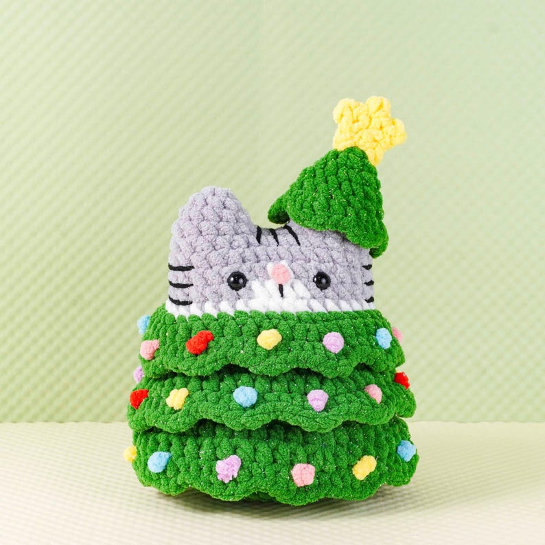 Peut inclure: Ornement de No&euml;l en forme de chat crochet&eacute;. Le chat gris a des rayures noires et un visage blanc. L'arbre vert a des pompons color&eacute;s et une &eacute;toile jaune. D&eacute;coration faite &agrave; la main.