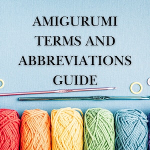 以下が含まれることがあります： 「Amigurumi Terms and Abbreviations」というタイトルのガイドで、カラフルな糸玉と編み棒が描かれています。テキストは黒で、薄い青色の背景に表示されています。糸の色には、赤、オレンジ、黄色、緑、青が含まれています。