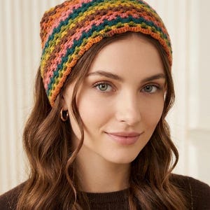 May include: A colorful, crocheted headband in shades of orange, pink, green, and yellow. The handmade accessory is worn on the head and has a textured appearance. The headband is a stylish accessory for any outfit.