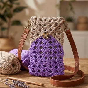 Może przedstawiać: Ręcznie robiona szydełkowa torba na ramię w kolorze beżowym i fioletowym, z geometrycznym ażurowym wzorem. Torba ma brązowy skórzany pasek i zapięcie na guzik. Widoczne są włóczka i szydełko, sugerujące motyw rzemieślniczy.