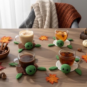 Könnte beinhalten: Eine herbstliche Szene mit vier Tassen Kaffee und Tee auf einem Holztisch. Jede Tasse steht auf einem handgefertigten grünen Schildkröten-Untersetzer. Dekorative Kürbisse, Herbstblätter und eine Schüssel mit Gewürzen.