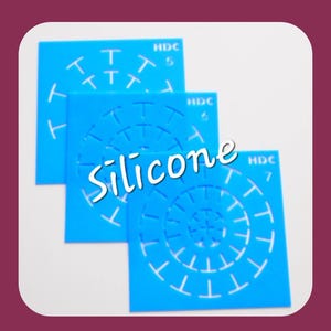 Op de afbeelding: Drie blauwe siliconen sjablonen met witte spiraalontwerpen en het woord "Silicone". Elke sjabloon heeft een ander nummer erop gedrukt. De sjablonen staan op een witte achtergrond met een bordeauxrode rand.