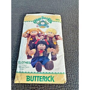 May include: A vintage Butterick pattern for Cabbage Patch Kids clothes. The pattern envelope features illustrations of three Cabbage Patch Kids dolls wearing various outfits. The text "CLOTHES For your Cabbage Patch Kids!" is visible.