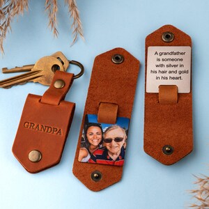 May include: A brown leather keychain with a photo insert, a small tag that says "GRANDPA", and a larger tag with the text "A grandfather is someone with silver in his hair and gold in his heart."