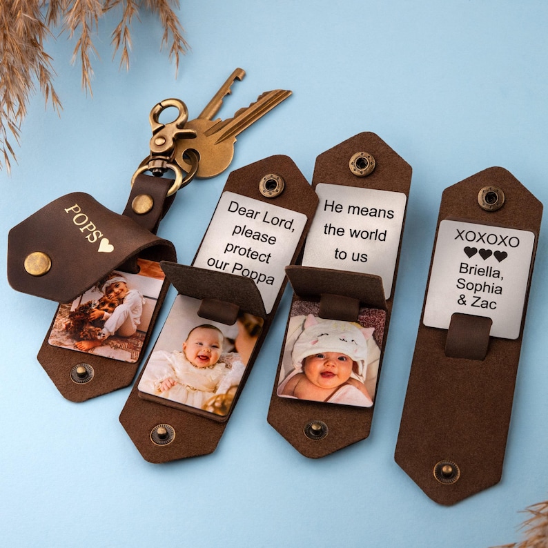 May include: Four brown leather keychains with a metal insert. Each keychain has a different inscription: "POPS", "Dear Lord, please protect our Poppa", "He means the world to us", and "XOXOXO Briella, Sophia & Zac".