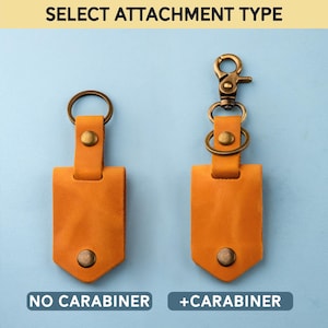 May include: Two leather keychains with a choice of attachment types: one with a metal carabiner and one without. Both keychains are tan leather with a brass ring and a brass rivet.
