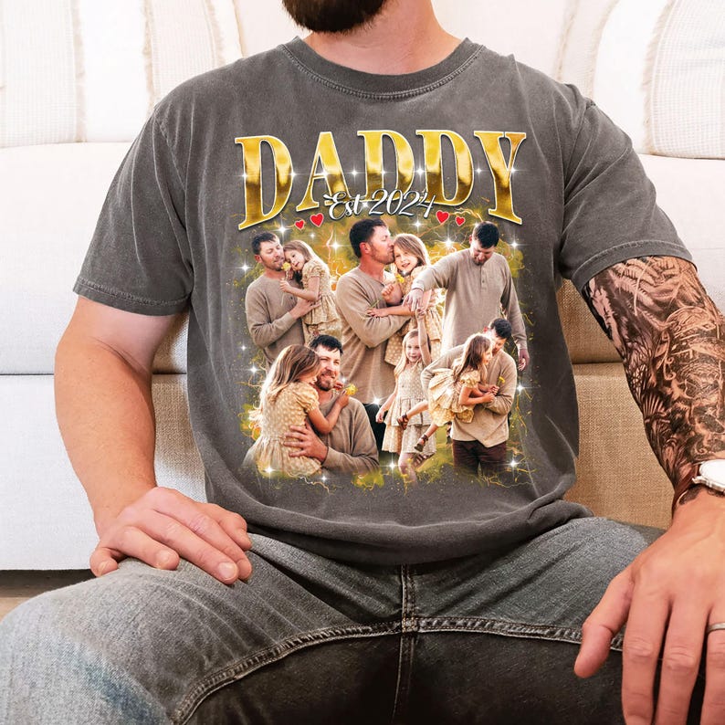 May include: Dark gray t-shirt with a gold "DADDY Est 2024" graphic. The graphic features a collage of family photos with a father and daughter. The shirt is made of a soft material and has a vintage look.