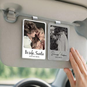 May include: Two clear, rectangular car visor photo holders with photos of couples. One has the text "Be safe, Sweetie" and "LOVE YOU MUCH." The other says "Drive safe Handsome" and "LOVE, EMILY."