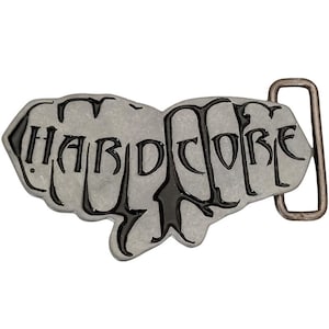 May include: A silver belt buckle with a raised design of two fists forming the word "HARDCORE" in black lettering.