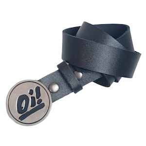 Puede incluir: Un cinturón de cuero negro con una hebilla plateada que presenta la palabra "Oi!" en un diseño gráfico en blanco y negro.