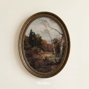 May include: An oval framed landscape painting depicting a forest scene with trees in autumn colors. The painting has a gold-colored frame and is mounted on a white wall. The painting includes the text "lueline" at the bottom.