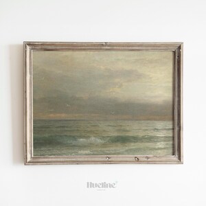 May include: A framed vintage seascape painting. The artwork depicts a cloudy sky over a turbulent ocean with visible waves. The frame is a distressed, light-colored wood.