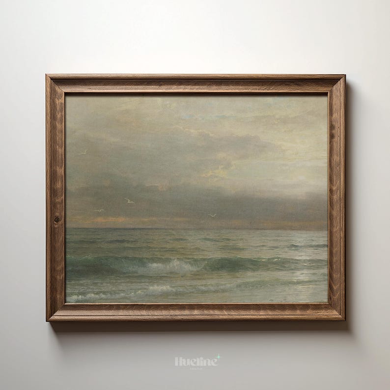 May include: A framed seascape painting depicts a cloudy sky over a turbulent ocean. The artwork features muted tones of gray, blue, and brown, with visible brushstrokes. The wooden frame adds a rustic touch to the coastal scene.