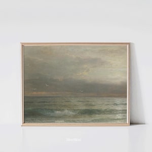 May include: A framed vintage seascape painting. The artwork depicts a moody ocean scene with waves, seagulls, and a cloudy sky. The color palette is muted, with shades of gray, green, and beige. The frame is a light gold color.