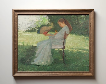 May include: A framed painting depicts a person seated in a chair, holding a fan. The person wears a light blue dress and is in a garden setting. The artwork is in a wooden frame, with a white fence and green foliage in the background.