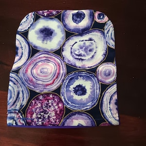 Funda para bolsa de ostomía con diseño de remolinos morados. Brida de 3&quot; x 8&quot; de largo. Parte inferior abierta y totalmente forrada con elástico. Adecuada para bolsas de ostomía más pequeñas.