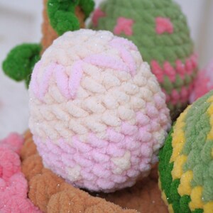 May include: A close-up of a pink and white yarn ball with a glittery texture. The ball is surrounded by other yarn balls in various colors, including green, brown, and yellow.