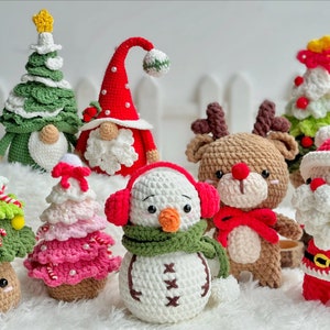 May include: A collection of crocheted Christmas ornaments, including a snowman, reindeer, Santa Claus, and several Christmas trees. The ornaments are made with a variety of colors, including red, green, white, and brown.