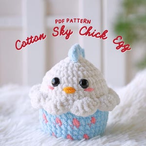 May include: A crochet amigurumi pattern for a sky blue chick in an egg shaped cupcake. The pattern is called "Cotton Sky Chick Egg" and is available as a PDF download.