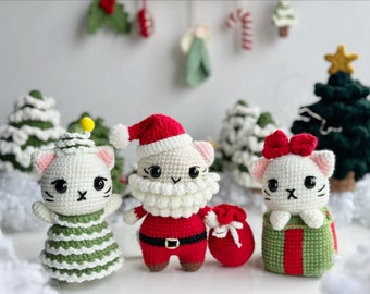 May include: Three crocheted cat ornaments dressed in Christmas attire. One cat is wearing a green and white Christmas tree costume, another is dressed as Santa Claus, and the third is holding a green and red gift box.