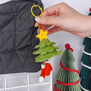 Op de afbeelding: Een handgemaakte kerstboom sleutelhanger met een gele ster, groene boom en rode sok accenten. De sleutelhanger is bevestigd aan een gele ring. Een feestelijk vakantieaccessoire.