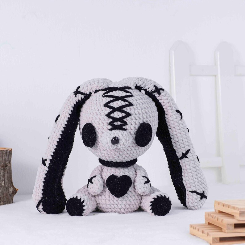 May include: A handmade crochet bunny doll in light gray and black. The bunny has large, floppy ears with black accents, black eyes, and a black heart on its chest. The doll is approximately 12 inches tall.