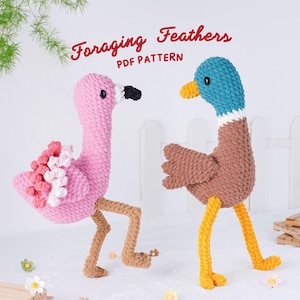 May include: Two handmade crochet bird figures: a pink flamingo and a brown duck. The flamingo has a black beak and white and pink accents. The duck has a blue head and yellow feet. The text "Foraging Feathers PDF Pattern" is above the birds.