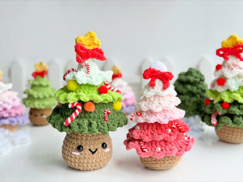 May include: A collection of handmade crocheted Christmas tree ornaments. The ornaments are made in various colors, including green, red, white, and pink. Each ornament features a cute face and is decorated with candy canes, beads, and pom-poms.
