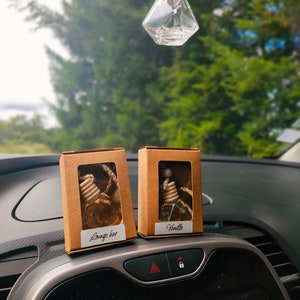 May include: Two small cardboard boxes containing car air fresheners. The boxes are brown with white text. The left box says "Lounge bar" and the right box says "Vanilla".