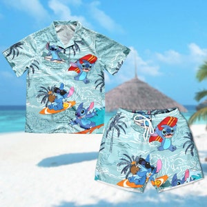 Op de afbeelding: Een blauw en wit Hawaiiaans overhemd en bijpassende shorts met een cartoonfiguur dat surft. Het figuur is blauw met grote oren en draagt een zonnebril. Het overhemd heeft een knoopsluiting en korte mouwen. De shorts hebben een elastische tailleband en een trekkoord.