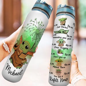 May include: A white water bottle with a green and brown illustration of a character from the Star Wars franchise. The bottle has a blue lid and a green and white dandelion design. The bottle has a motivational quote on the side that reads "Get Started, Remember your goal, Keep chugging, Don't give up, Almost There, You did it, Refill Now". The bottle is personalized with the name "Michael".