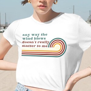 May include: White cropped t-shirt with a retro-style graphic that says "any way the wind blows doesn't really matter to me". The graphic features a rainbow design with red, orange, yellow, green, and blue stripes.